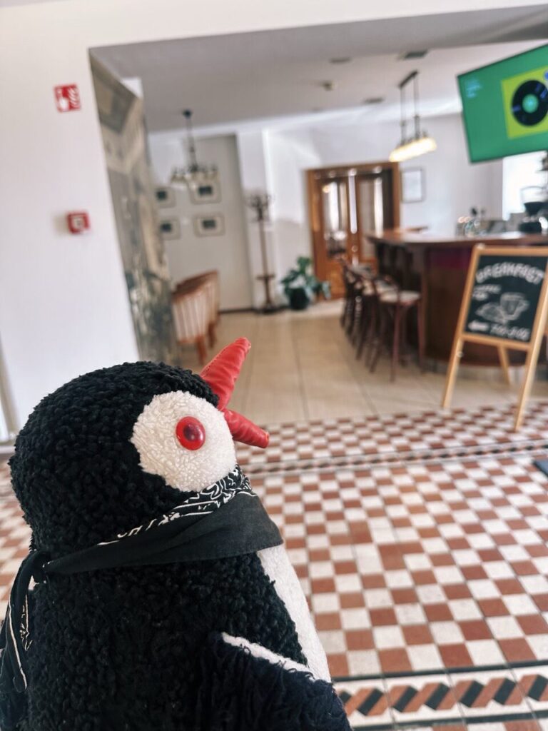 The plush penguin toy Miško sits in a hotel lobby during a Slovenia road trip