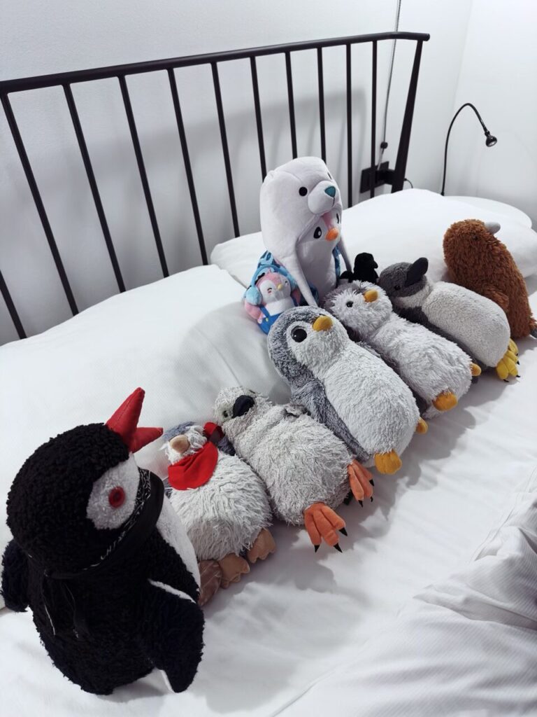 A collection of plush penguin toys arranged on a white bed