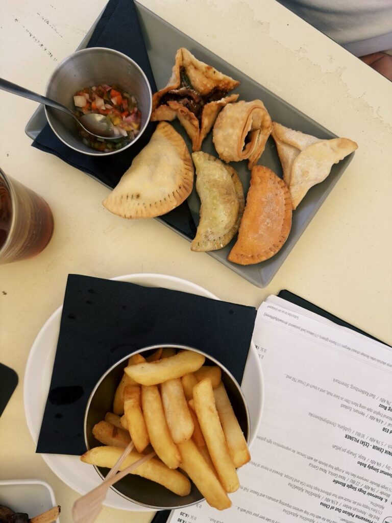 A plate of empanadas and a bowl of fries on a table