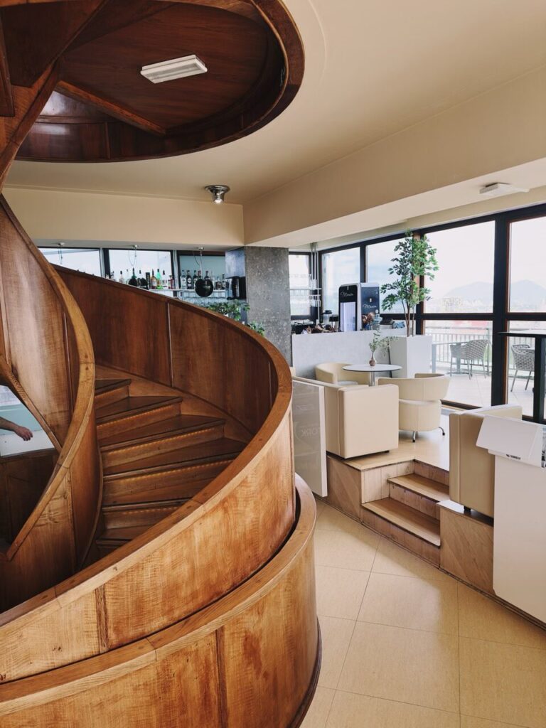 Wooden spiral staircase in a modern restaurant with views of the outdoors
