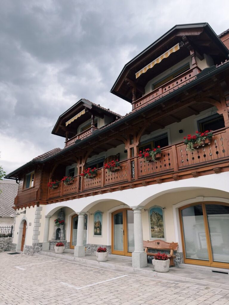 Traditional wooden building with flower-filled balconies in Slovenia under a cloudy sky