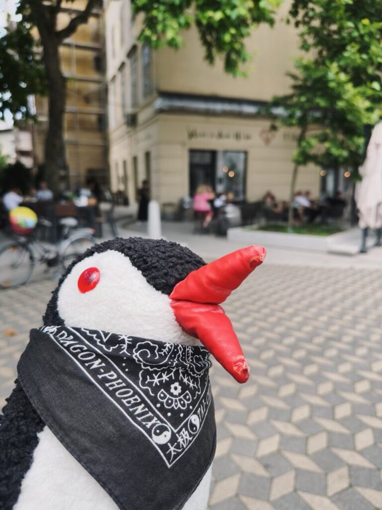 Plush penguin with a red beak wearing a black and white bandana in Slovenia