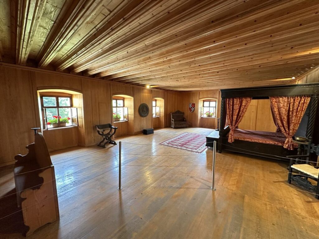 A wood-paneled bedroom inside Predjama Castle features a canopy bed and antique furniture