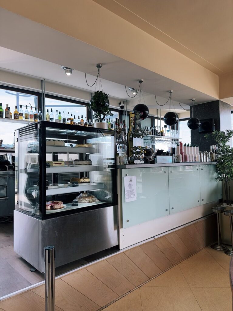 Glass display case filled with cakes next to a modern bar in Slovenia