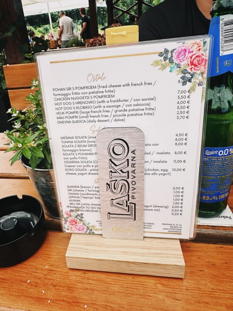 Menu with prices and a beer bottle on a wooden restaurant table