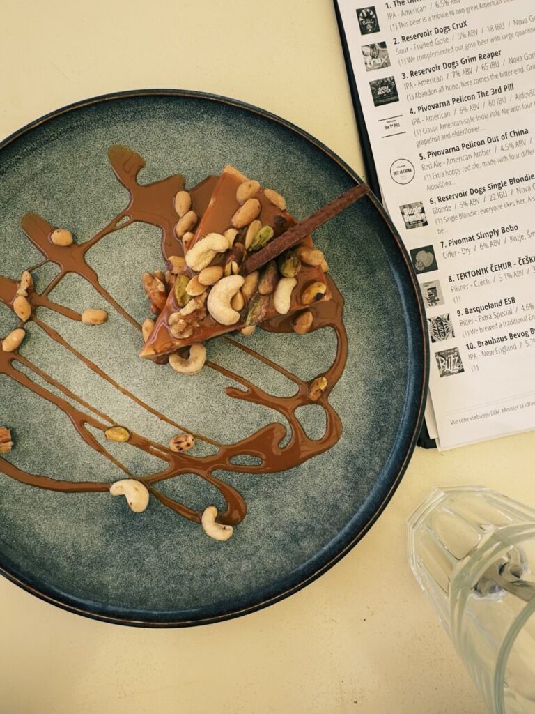 Slice of cake topped with nuts and caramel sauce on a blue plate