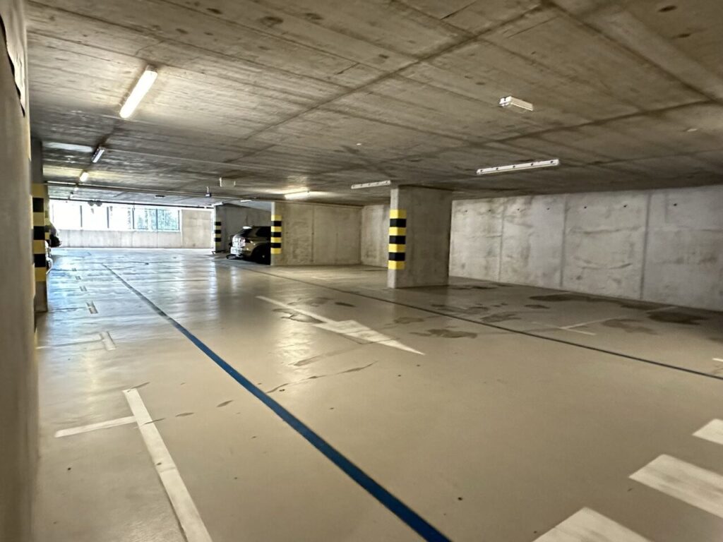 Concrete parking garage in Piran with striped pillars and a car in the background
