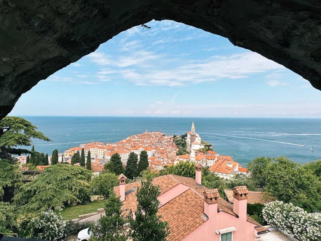 View of the coastal town of Piran framed by a stone archway