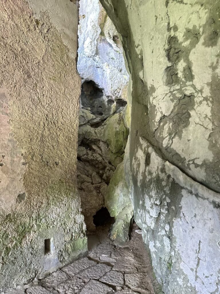 Stone walls of Predjama Castle enclose a narrow passage leading into a cave
