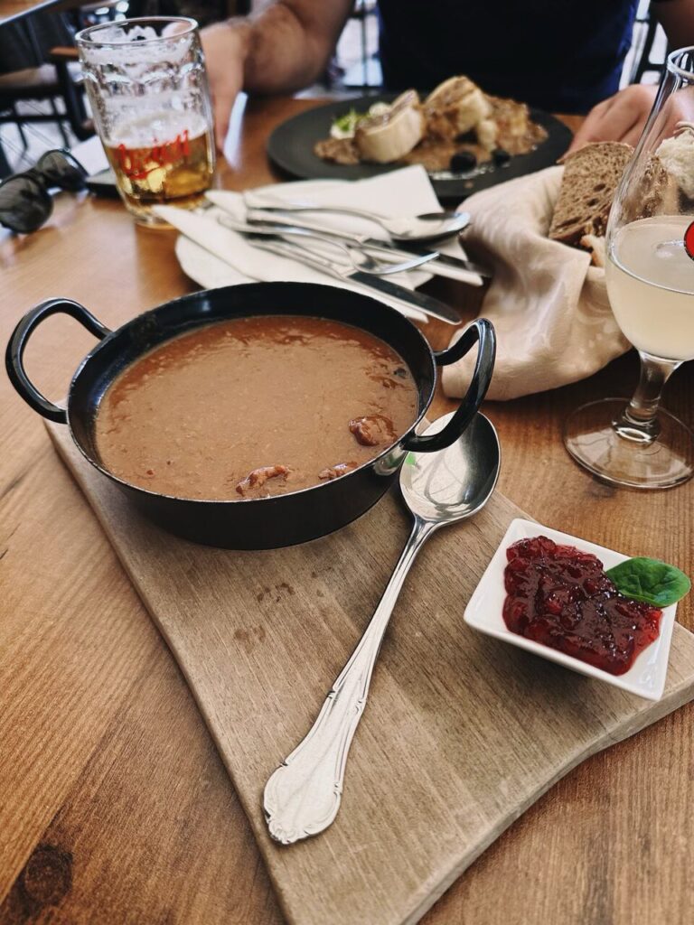 A small pan of stew served with a side of red jam in Slovenia