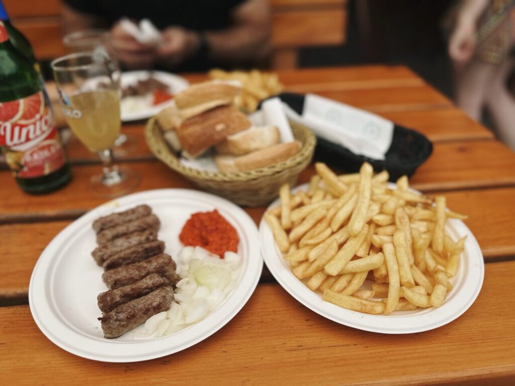 Plates of grilled meat, onions, and fries on a wooden table in Slovenia