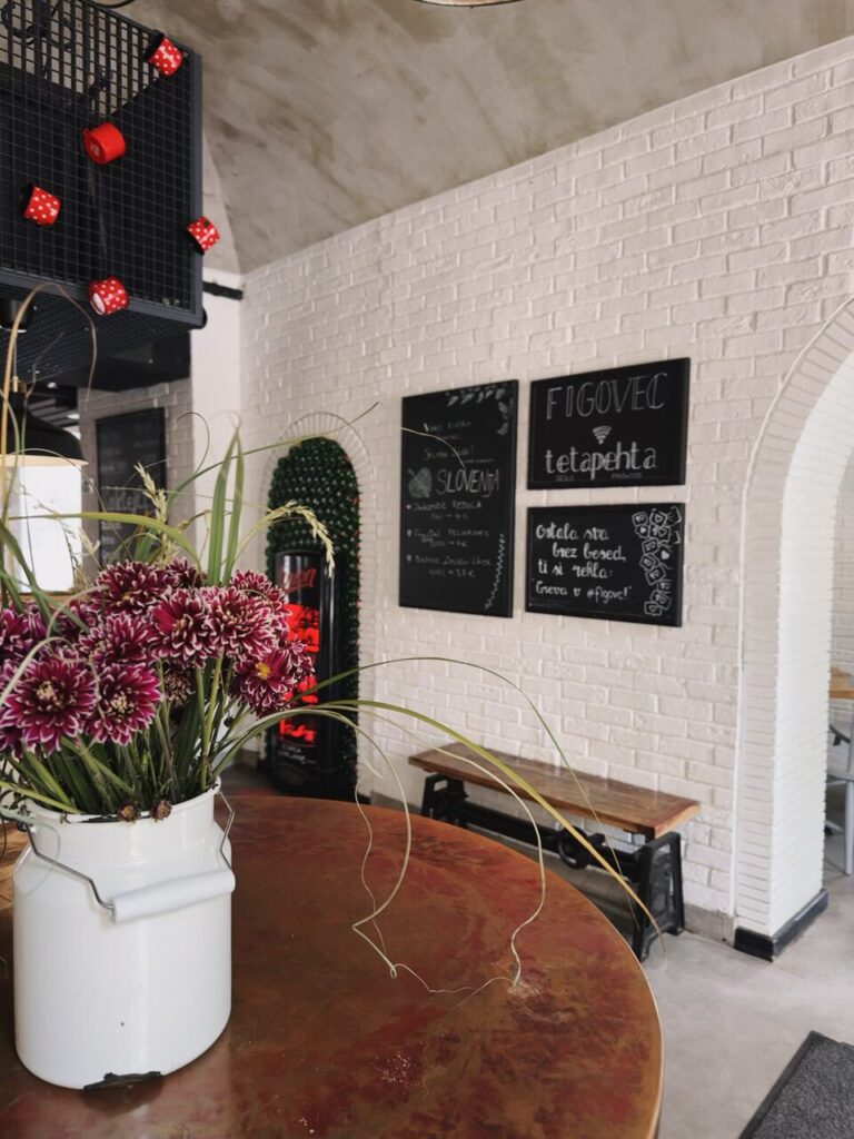 Flowers in a white pitcher sit on a table inside Figovec in Slovenia