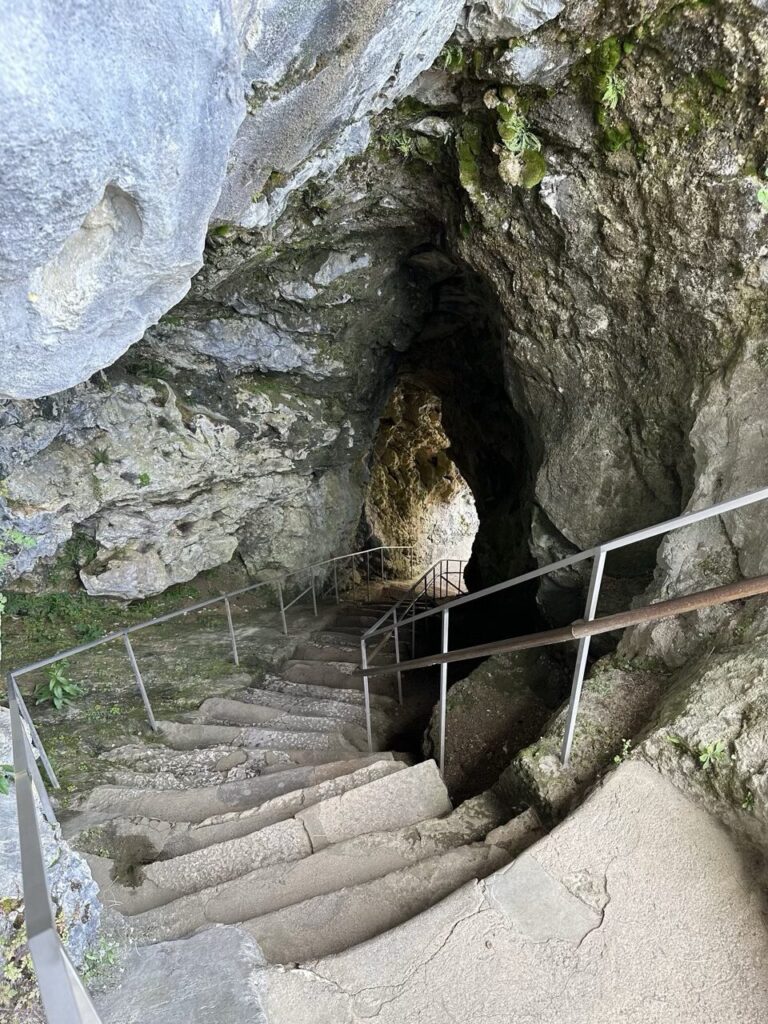 Stone stairs descend into a dark cave passage at Predjama Castle