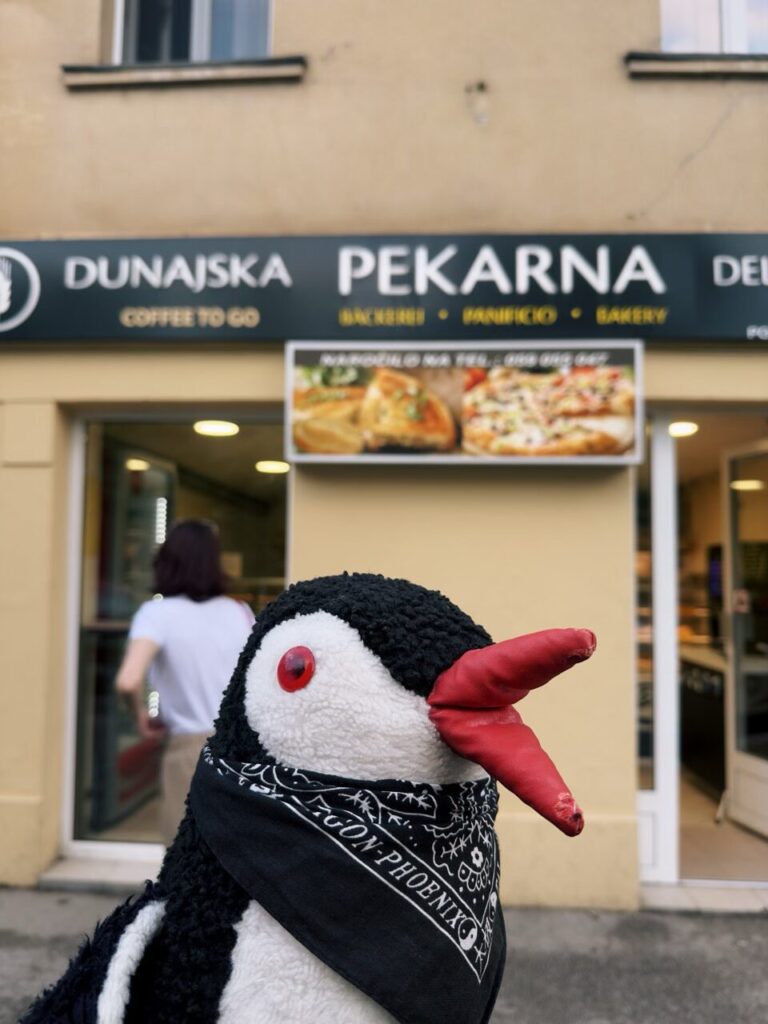 A plush penguin toy stands in front of a bakery in Slovenia