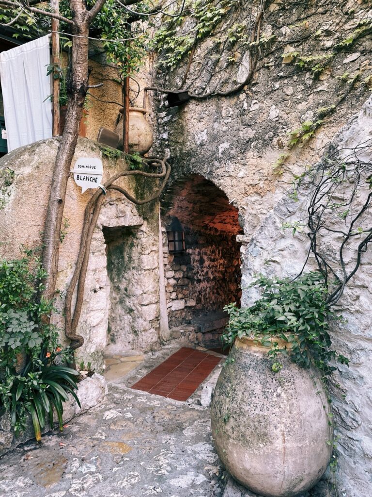 Stone archway with plants and a Dominique Blanche sign in Eze, France